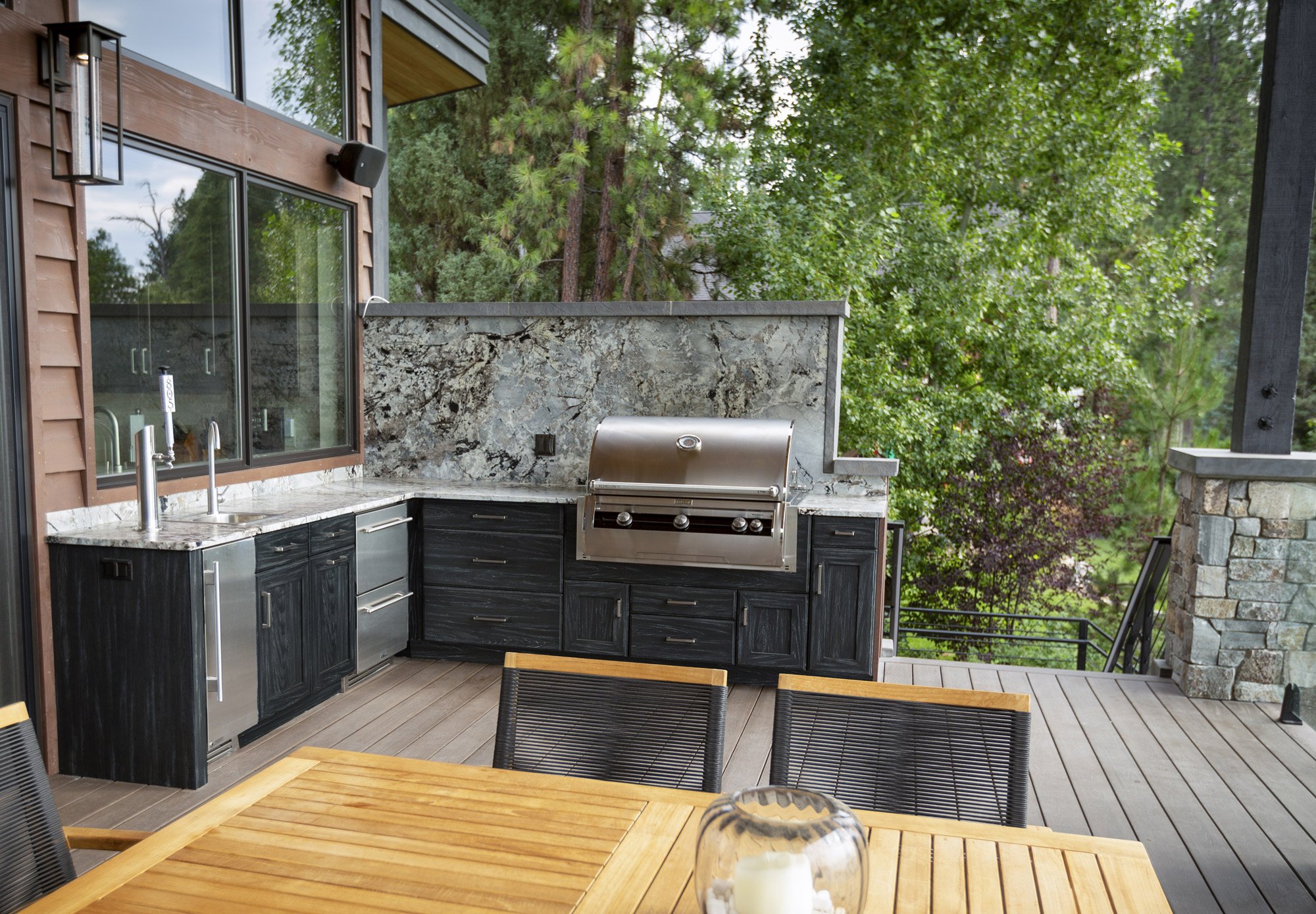 Weatherproof entertainment area with outdoor kitchen in a forest setting